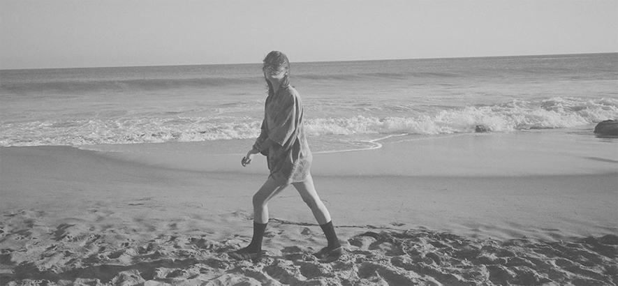 Schwarz-Weiss-Foto von Cate Le Bon – es zeigt die walisische Künstlerin an einem Strand