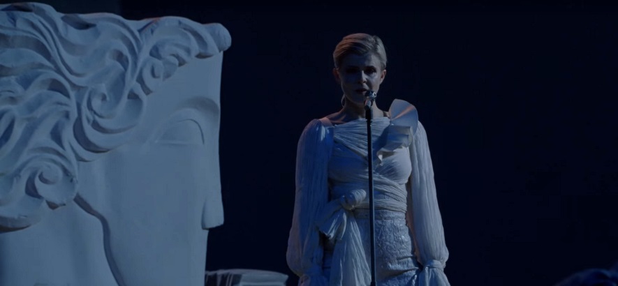 Die schwedische Electro-Pop-Künstlerin Robyn vor blauem Hintergrund neben einer altgriechisch anmutenden Statue