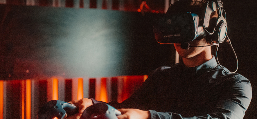 Foto eines Mannes, der eine VR-Brille trägt und einen Controller in der Hand hält