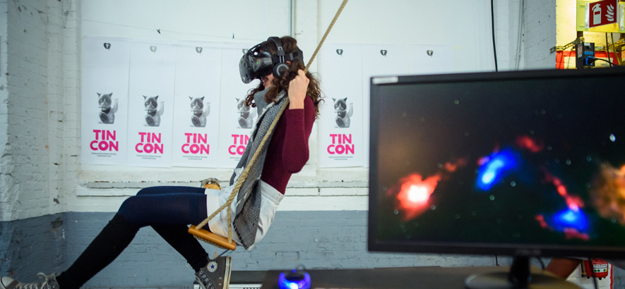 Foto einer jungen Frau, die bei der Tincon auf einer Schaukel schaukelt und dabei eine Virtual-Reality-Brille trägt