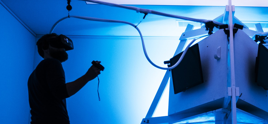Foto eines Mannes, der eine VR-Brille trägt und ein VR-Device bedient.