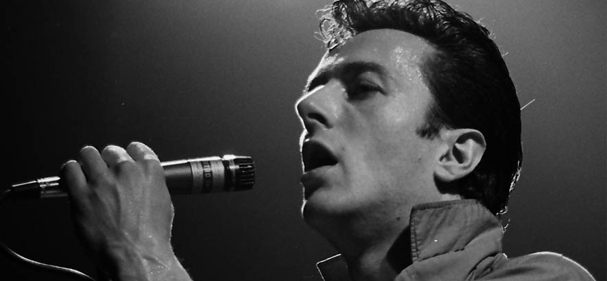 Foto von Joe Strummer, der heute 70 Jahre alt würde. Aus diesem Anlass ist der Song „Overpowered By Funk“ seiner Band The Clash unser Track des Tages.