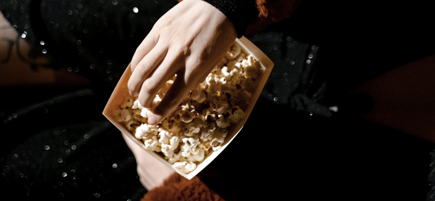 Foto einer Hand, die in eine Tüte Popcorn greift