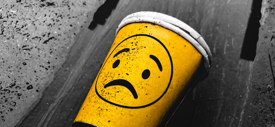 Foto eines Pappbechers mit einem traurigen Smiley