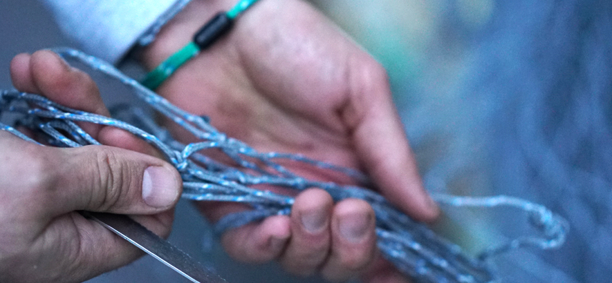 Foto von einer Hand, die ein altes Fischernetz hält