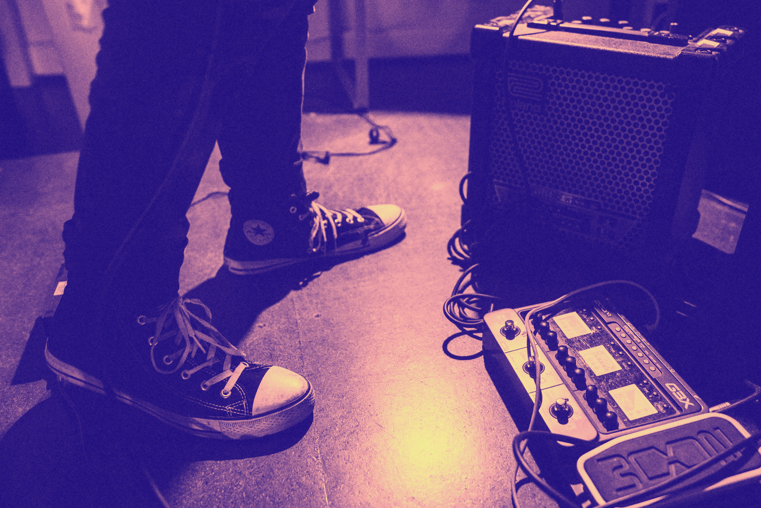 Foto, auf dem die Beine und Schuhe einer Person sowie Musikequipment zu sehen ist